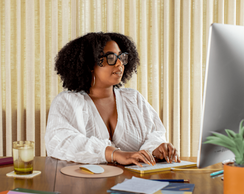 A woman in her home office, reaching out to her Mailchimp Customer Success manager via her computer.