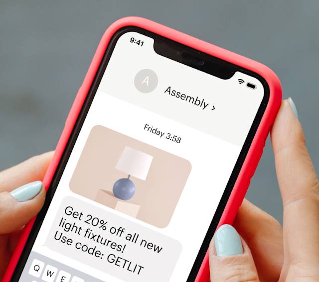 iPhone with red case showing Assembly app interface displaying a 20% off lighting fixtures promotion with discount code GETLIT