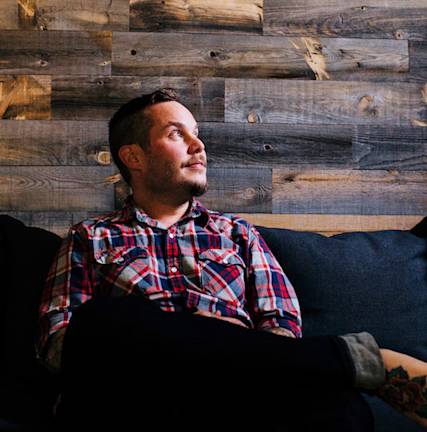 A photo of Paul Jarvis sitting on a couch, looking away from the camera.