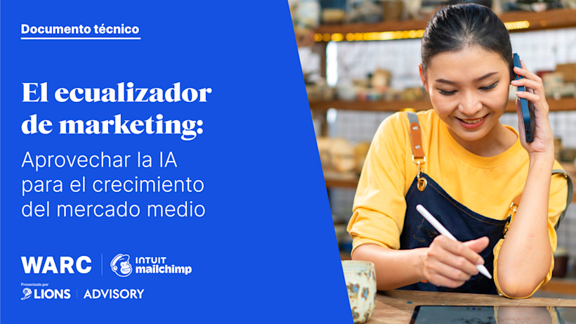 Propietario de negocio con suéter amarillo tomando notas mientras habla por teléfono, junto a un documento técnico sobre marketing con IA en fondo azul