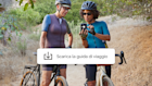 Due donne in un tour in bicicletta, in un momento di pausa per scaricare un’app di guida di viaggio offerta dalla campagna di Mailchimp.