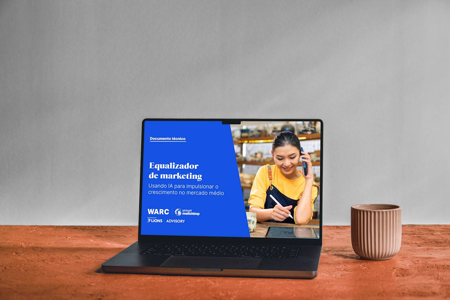 Laptop mostrando o whitepaper "O equalizador de marketing" em fundo azul, com tigelas de cerâmica sobre uma superfície de madeira