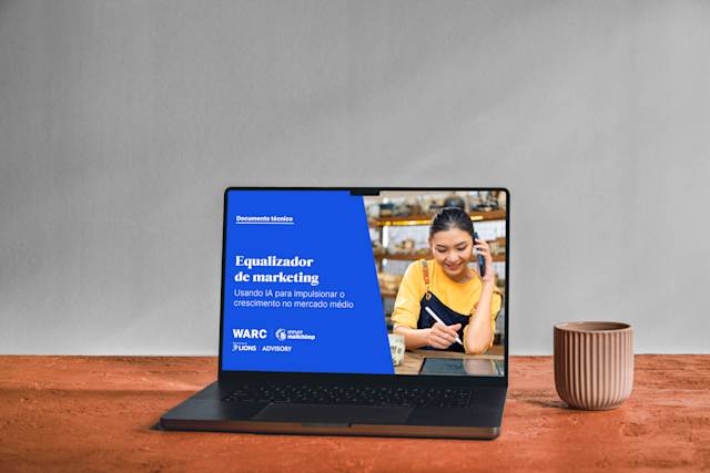 Laptop mostrando o whitepaper "O equalizador de marketing" em fundo azul, com tigelas de cerâmica sobre uma superfície de madeira