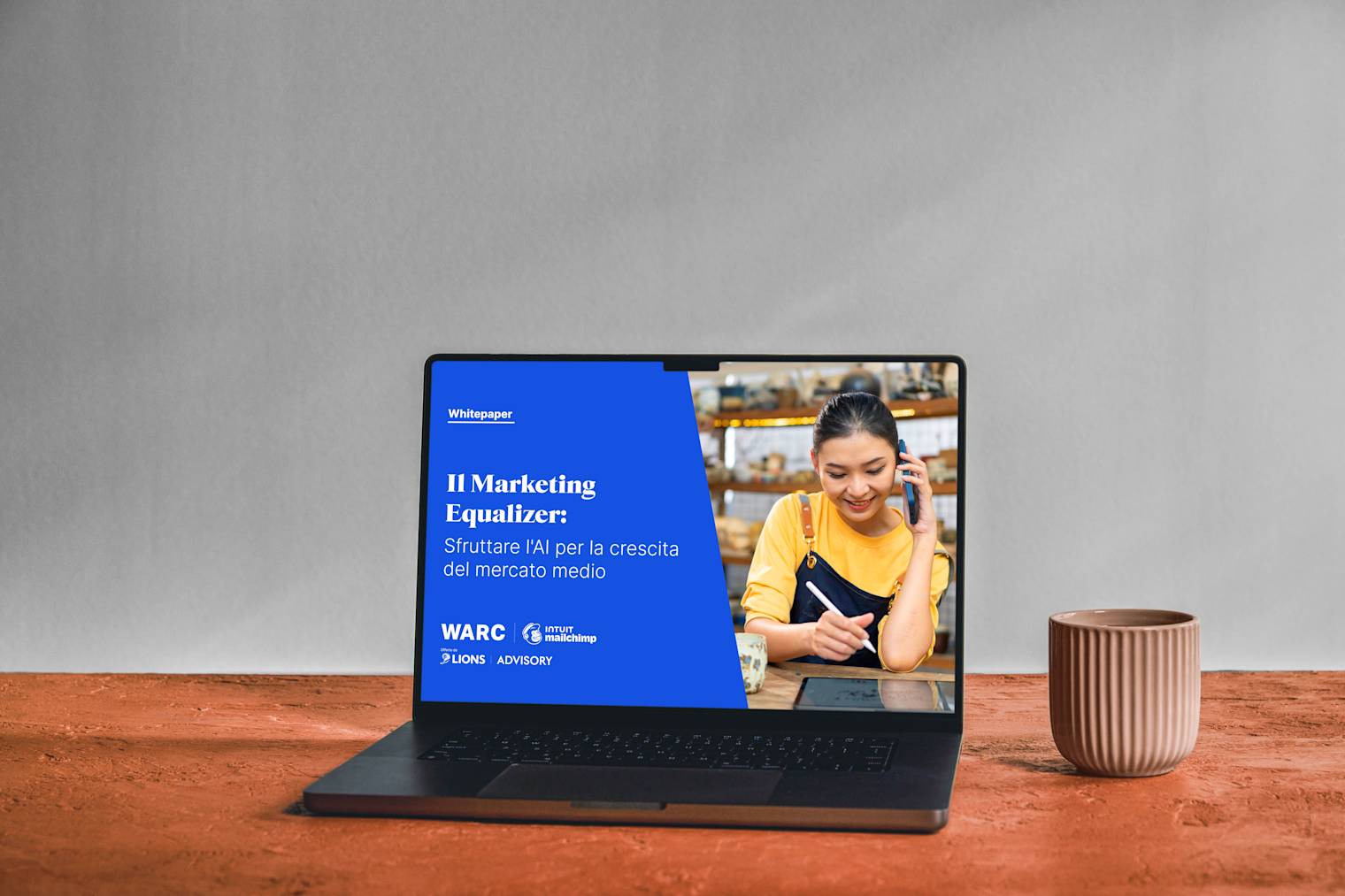 Laptop che mostra il white paper "The Marketing Equalizer" su sfondo blu, con ciotole in ceramica su superficie di legno