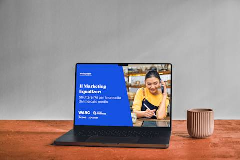 Laptop che mostra il white paper "The Marketing Equalizer" su sfondo blu, con ciotole in ceramica su superficie di legno