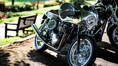Row of parked motorcycles in dappled sunlight, showing chrome details and classic styling from different angles