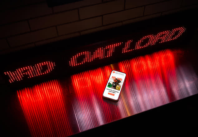 Smartphone displaying content floats against dramatic red and white LED light panel background with illuminated text above