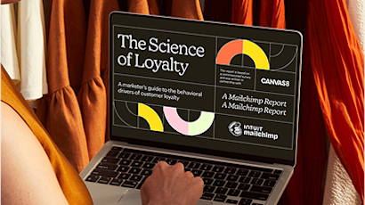 Laptop displaying "The Science of Loyalty" presentation with colorful geometric shapes on screen against orange fabric backdrop