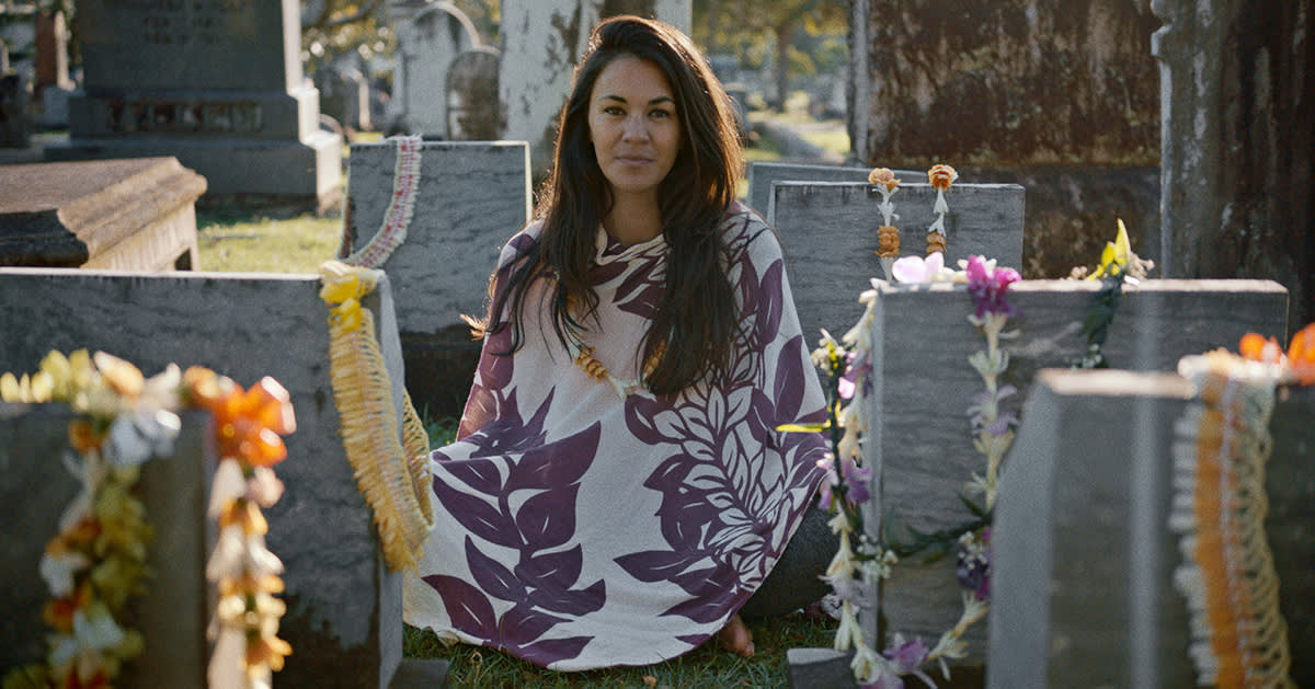 Courtney Gusick sitting between headstones in graveyard.