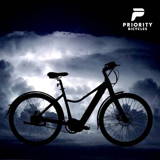 Silhouette of an electric bicycle against dramatic stormy sky with Priority Bicycles logo in top right corner