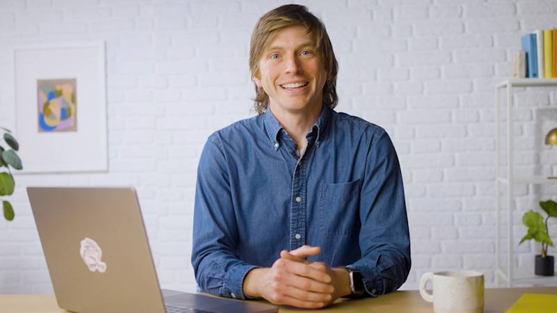 Mailchimp employee with a friendly expression seated at a table with an open laptop 