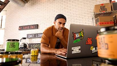Person working on laptop at Cat Lord, a cafe with exposed brick walls and retail shelves displaying coffee products