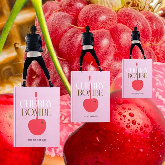 Three silhouetted figures stand on pink "Cherry Bombe" cookbooks against a backdrop of fresh red cherries and fruit