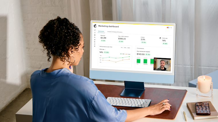 Person with curly hair viewing a marketing dashboard on computer screen showing revenue metrics, graphs, and performance data