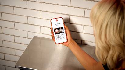 Hand holding a phone scanning a QR code on a white brick wall, showing multiple stages of the scanning process
